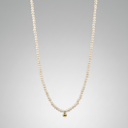 Pearl necklace with a gold pendant on a gray background
