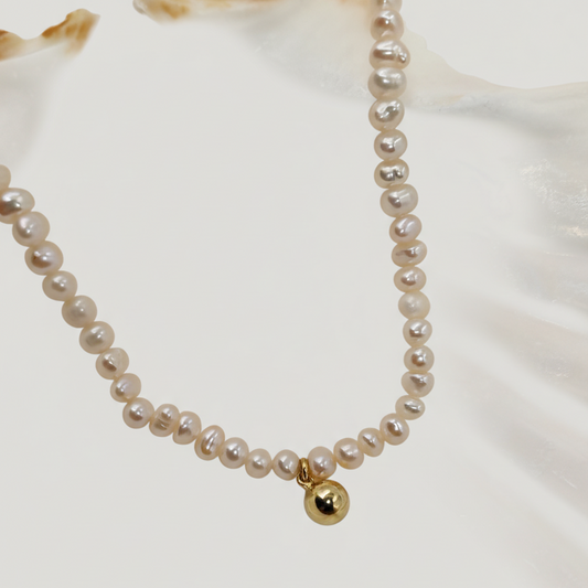 Pearl necklace with a gold bead on a white background