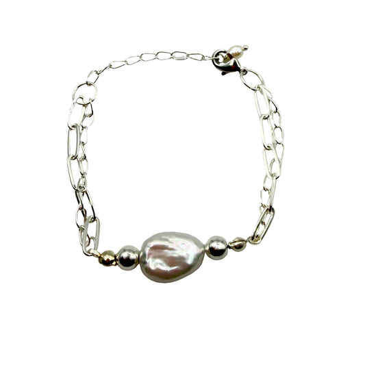 A silver-plated adjustable bracelet with a large, white baroque pearl pendant.