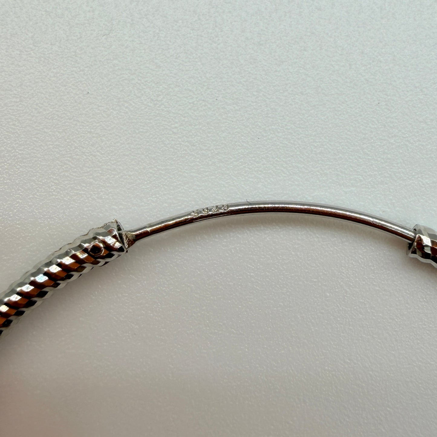 Close-up of twisted rope pattern and snap closure on 40mm silver hoop earrings with 925 stamp