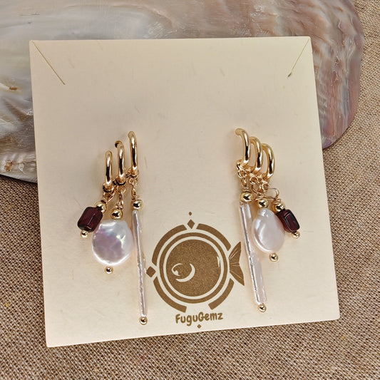 Pair of gold earrings with pearls and garnets on a Fugugemz branded card.