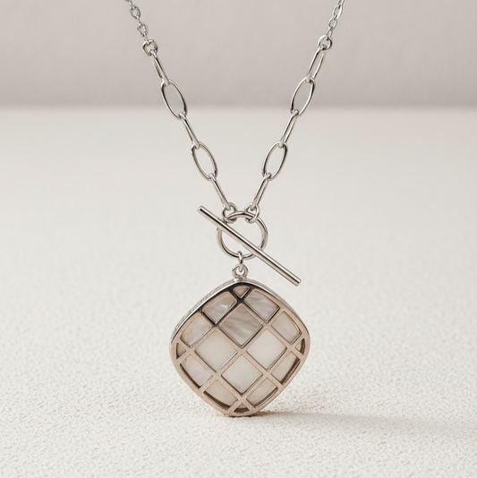 Silver necklace with a textured pendant on a light background