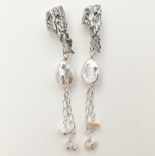 Woman wearing platinum and pearl earrings on ears