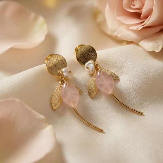 Gold earrings with pink stones on a soft pink fabric background