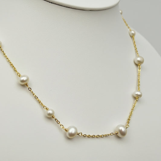 Pearl necklace with gold chain on a mannequin bust against a white background