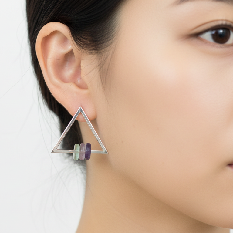 Triangle-shaped earring worn by a person on a white background