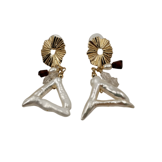 Pair of earrings with gold and black accents on a beige background