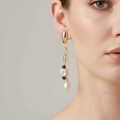 Gold earring with pearls worn by a model on a neutral background