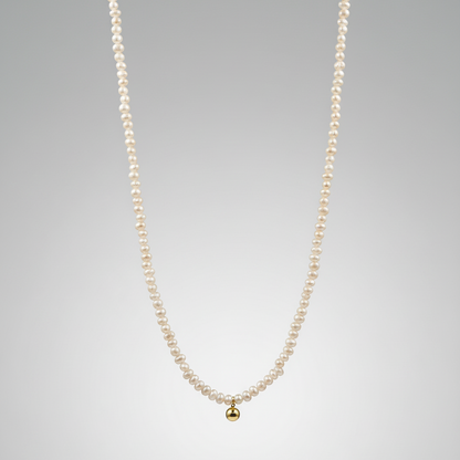 Pearl necklace with a gold pendant on a gray background