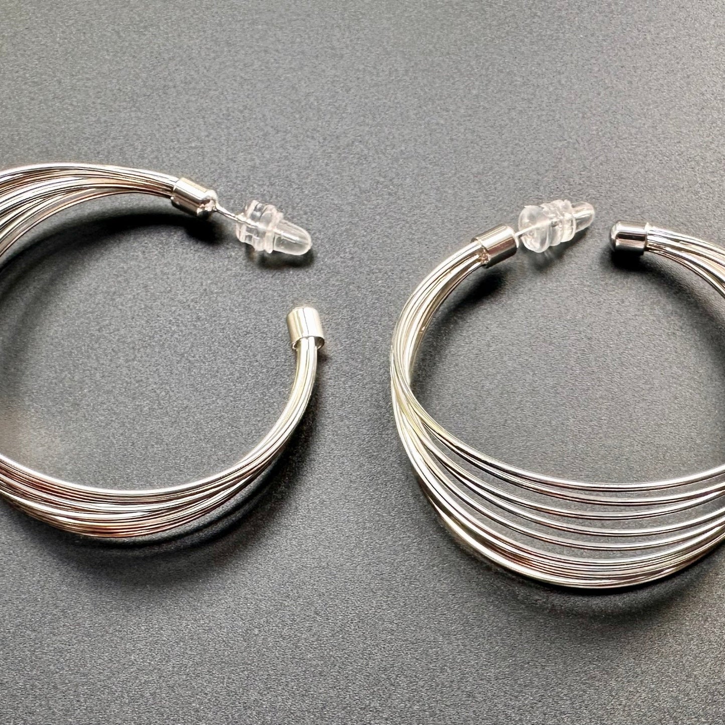 Pair of silver hoop earrings on a gray background