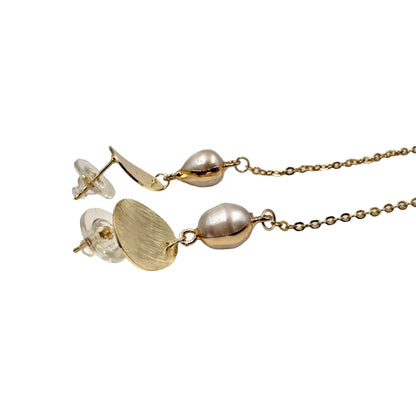 Gold necklace with beads and clear crystal on a light gray background