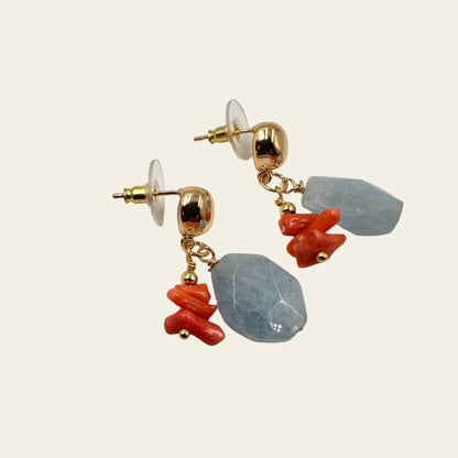 Pair of earrings with blue and orange stone-like beads on a white background