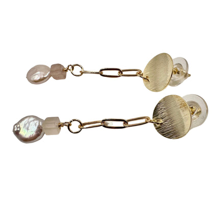Close-up of textured disc, pink quartz, and baroque pearl details
