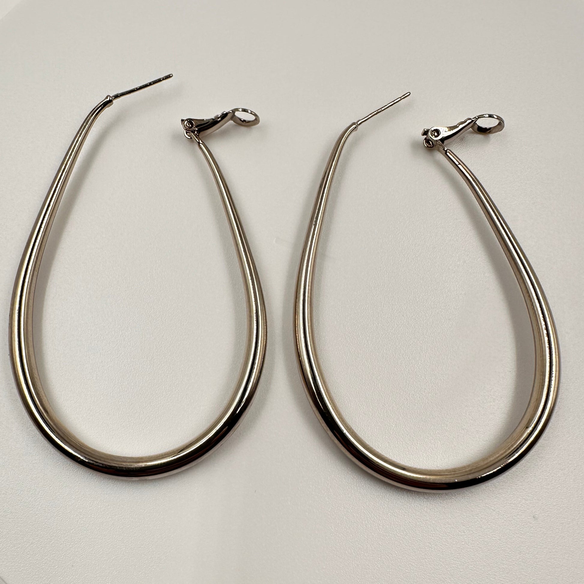 Pair of silver hoop earrings on a white plate