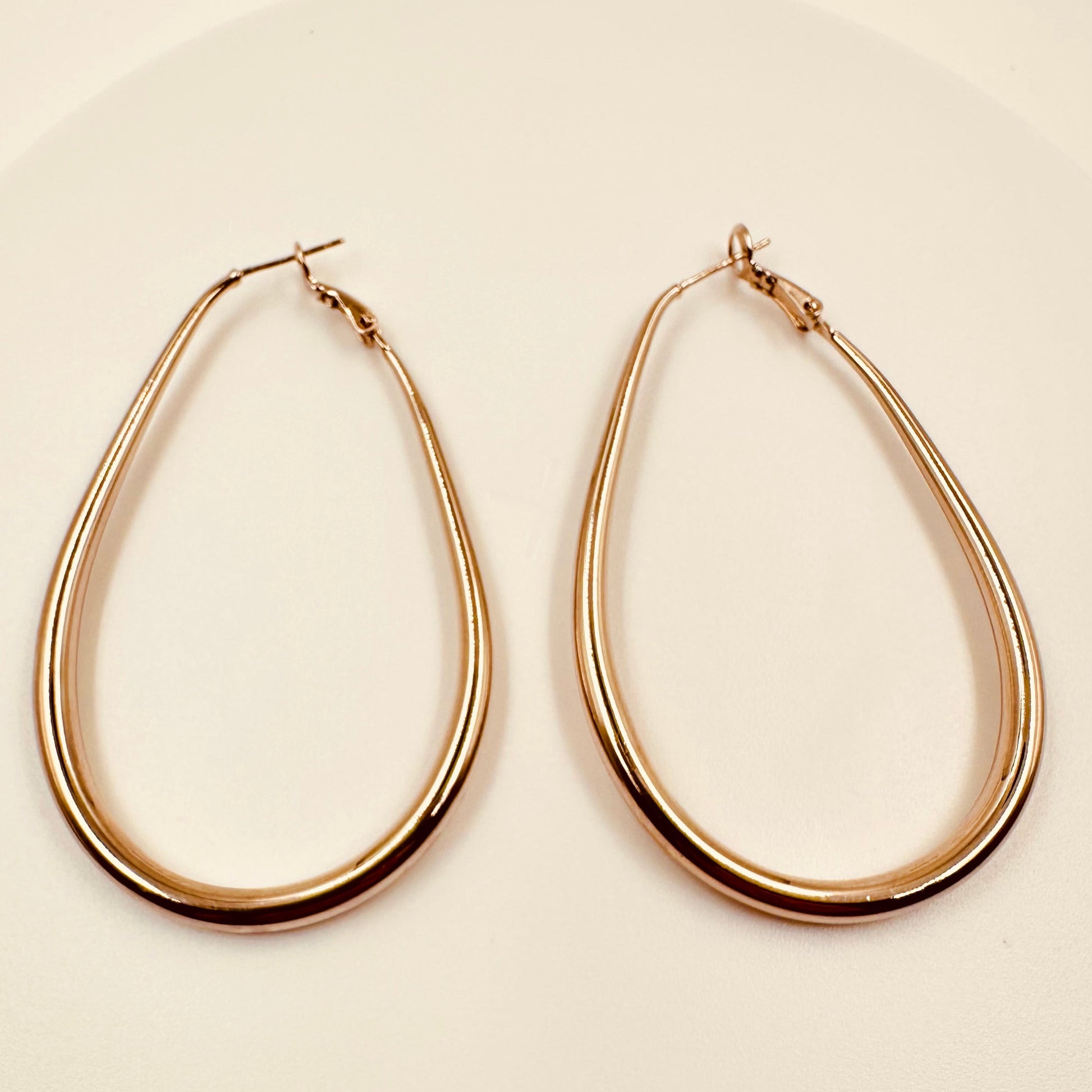 Gold hoop earrings on a beige background