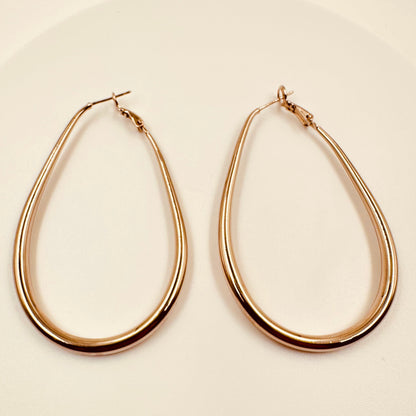 Gold hoop earrings on a beige background