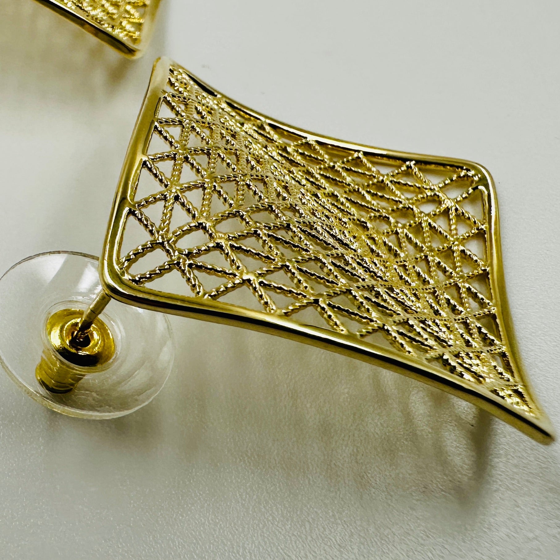 Gold geometric earring on a light gray background