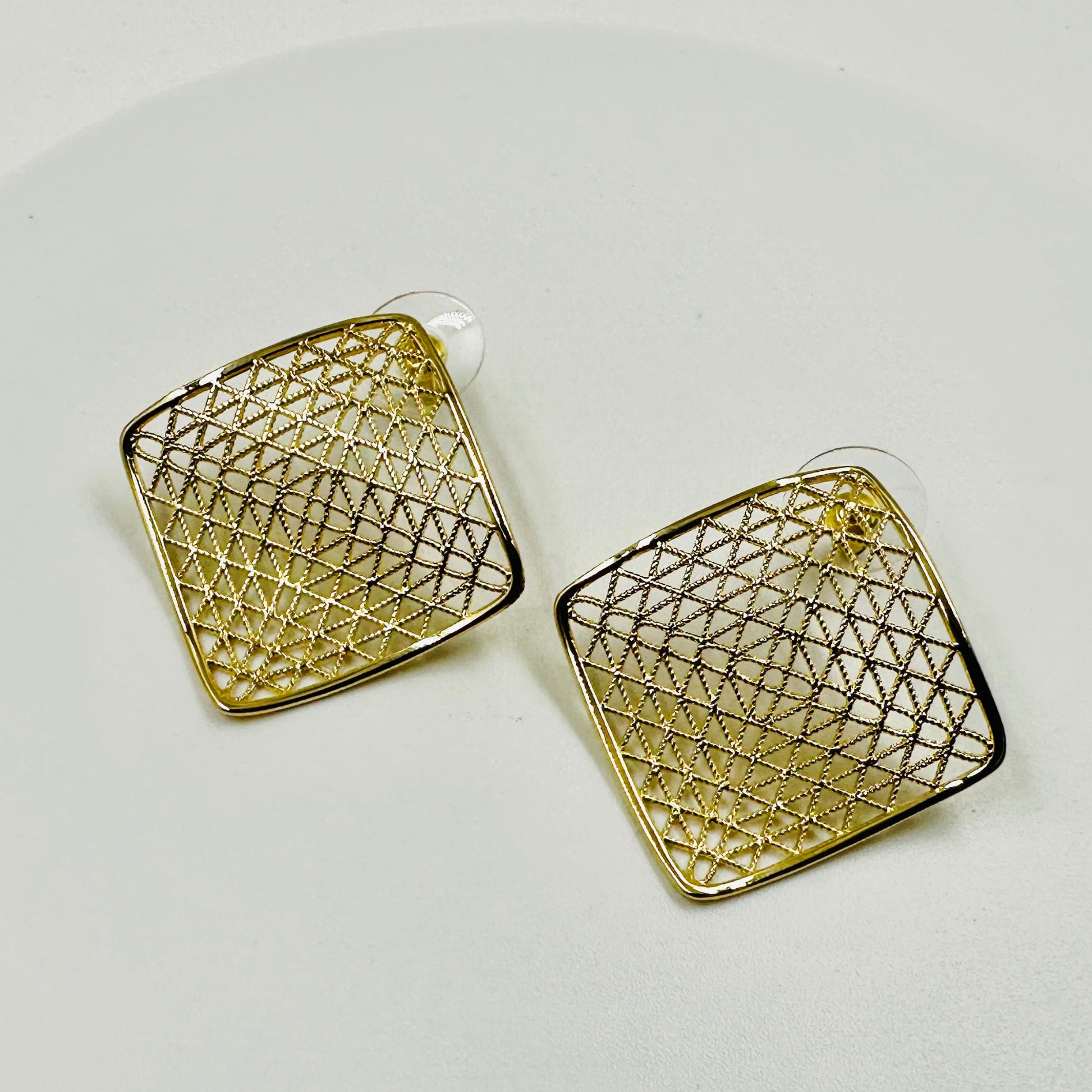 Gold geometric earrings on a light gray background