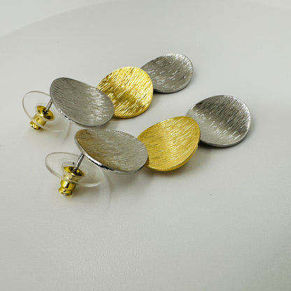 Pair of gold and silver earrings on a light gray background