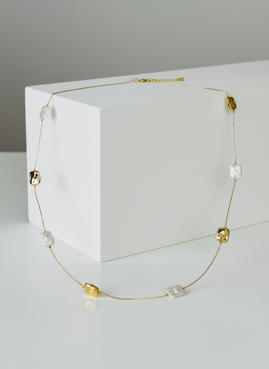 Gold necklace with beads on a white surface