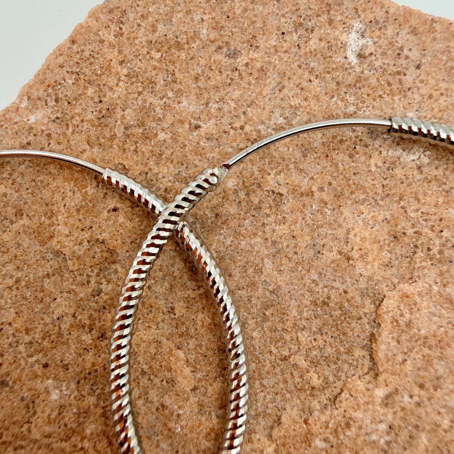Close-up of twisted rope pattern and endless closure on 40mm silver hoop earrings with 925 stamp
