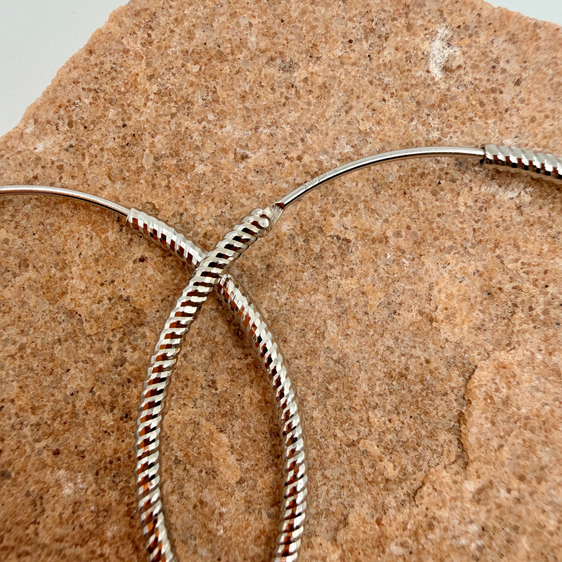 Close-up of twisted rope pattern and endless closure on 40mm silver hoop earrings with 925 stamp
