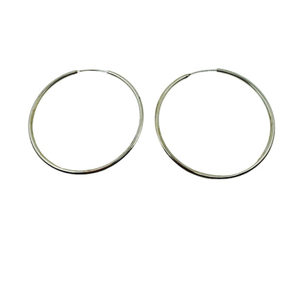 Pair of 55mm silver hoop earrings on a light gray background