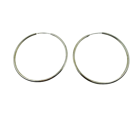 Pair of 55mm silver hoop earrings on a light gray background