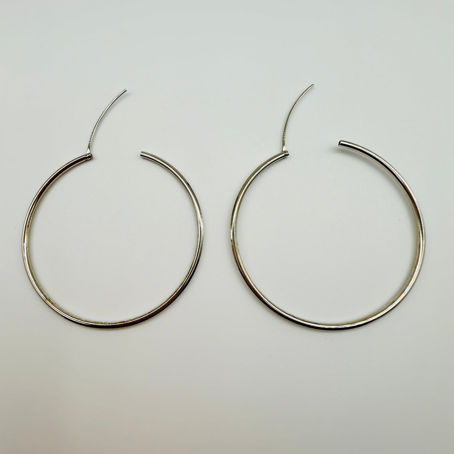 Pair of silver hoop earrings on a light gray background