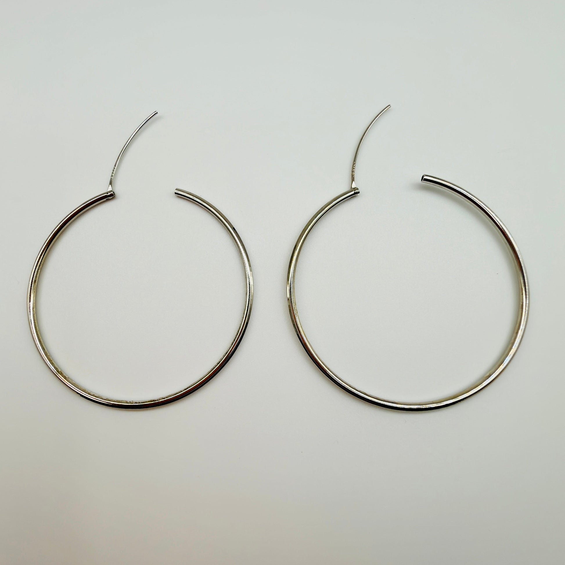 Pair of silver hoop earrings on a light gray background