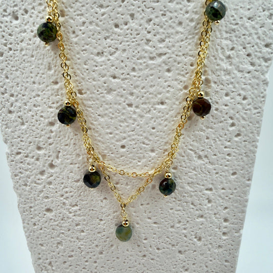 Gold necklace with green beads on a mannequin