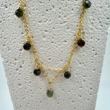 Gold necklace with green beads on a mannequin