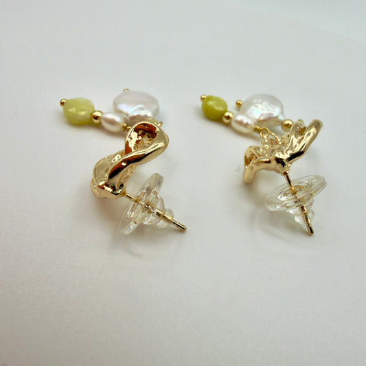 Pair of gold earrings with pearls and green beads on a light gray background