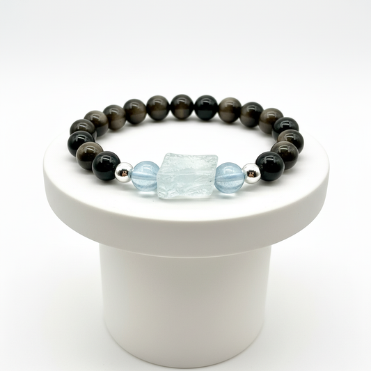 Beaded bracelet with obsidian and light blue aquamarine on a white pedestal