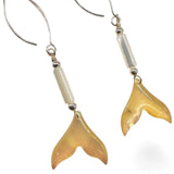 Pair of gold fish tail earrings on a white background