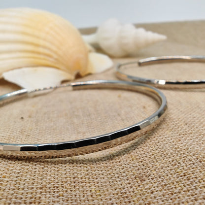 50mm sterling silver hammered hoop earrings on a natural stone background with seashells
