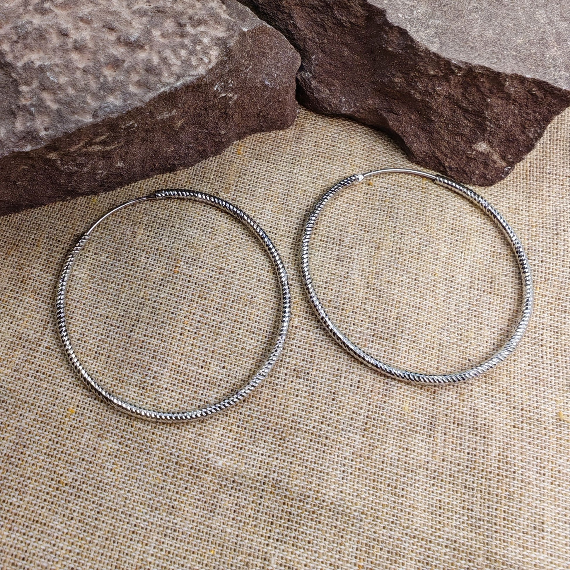 40mm sterling silver twisted rope hoop earrings on burlap background with rocks