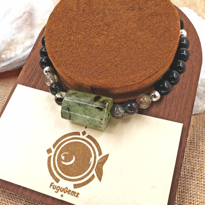 Close-up of rutilated quartz and obsidian beads with fugugemz logo