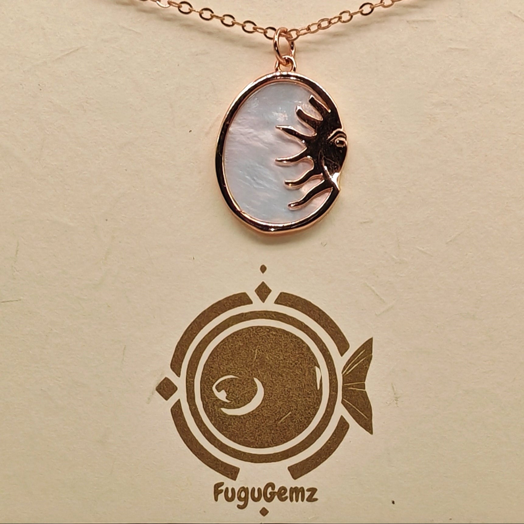 Close-up of oval pendant and sun face engraving on Fugugemz branding
