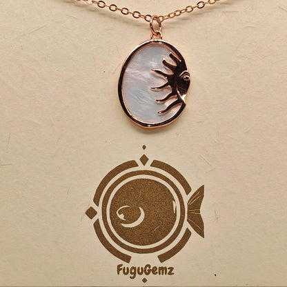 Close-up of oval pendant and sun face engraving on Fugugemz branding

