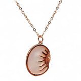 Close-up of oval pendant and sun face engraving
