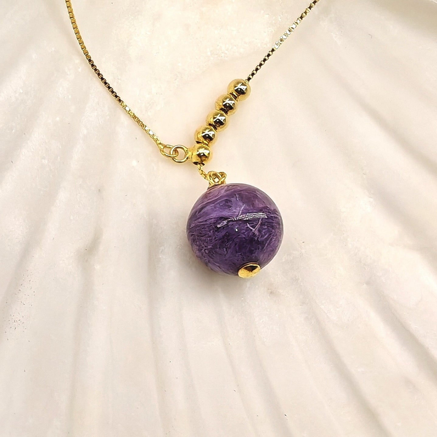 Close-up of charoite pendant and gold beads
