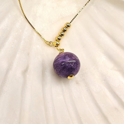Close-up of charoite pendant and gold beads
