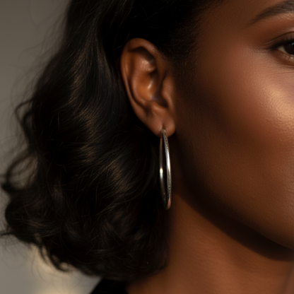 Woman wearing 50mm sterling silver hoop earrings with natural makeup and loose hair
