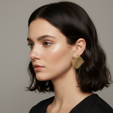 Woman wearing gold geometric mesh earrings with natural makeup and loose hair