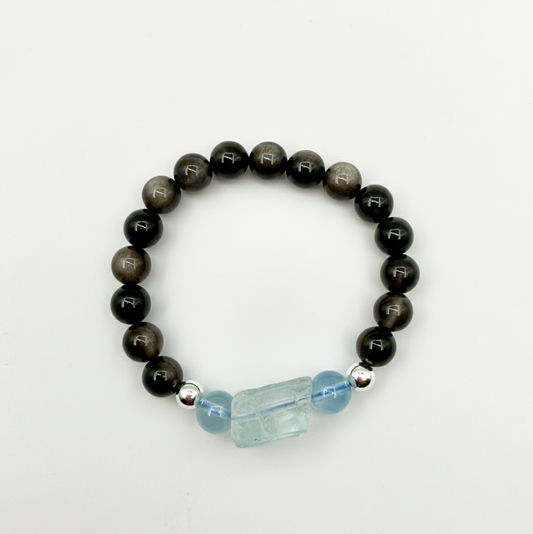 Black beaded bracelet with a blue crystal charm on a white background