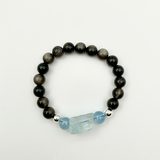Black beaded bracelet with a blue crystal charm on a white background