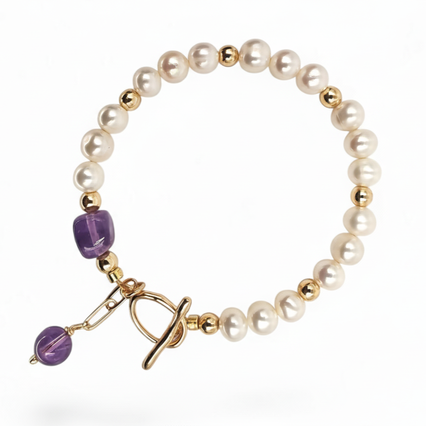 Bracelet with purple beads and gold accents on a wooden stand with a branded card underneath.