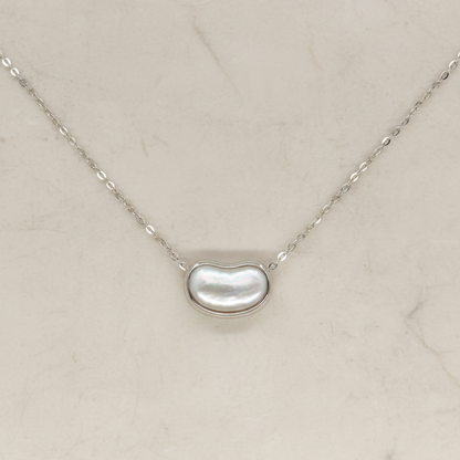 Necklace with a kidney-shaped pearl pendant on a light beige background