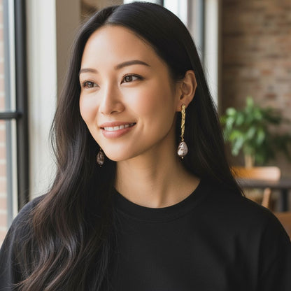 Woman wearing gold-plated purple baroque pearl earrings with long dark hair